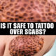 Is it safe to tattoo over scabs?